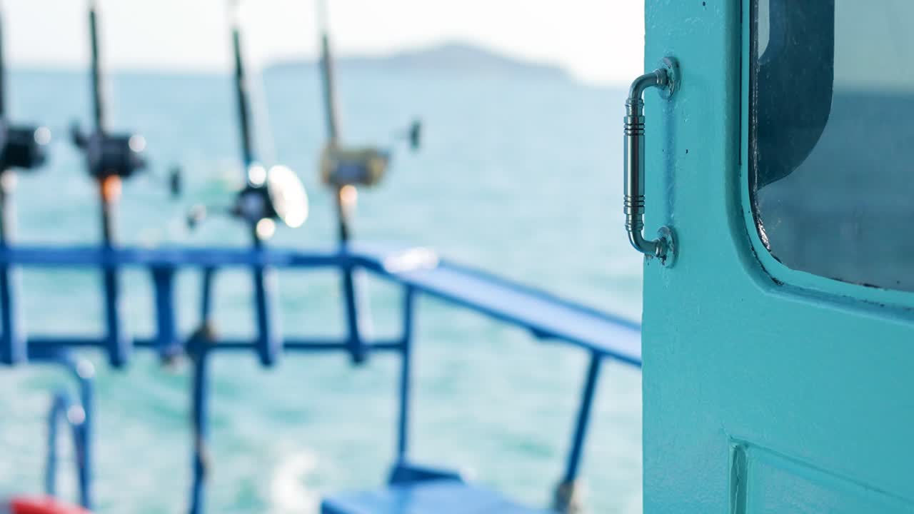 A fishing boat with rods against a calm ocean backdrop in Phuket, Thailand. Bright daylight enhances the tranquil maritime scene