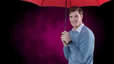 hombre sonriente poniendo un paraguas rojo y refugiándose debajo de él, sobre un fondo rosa y negro