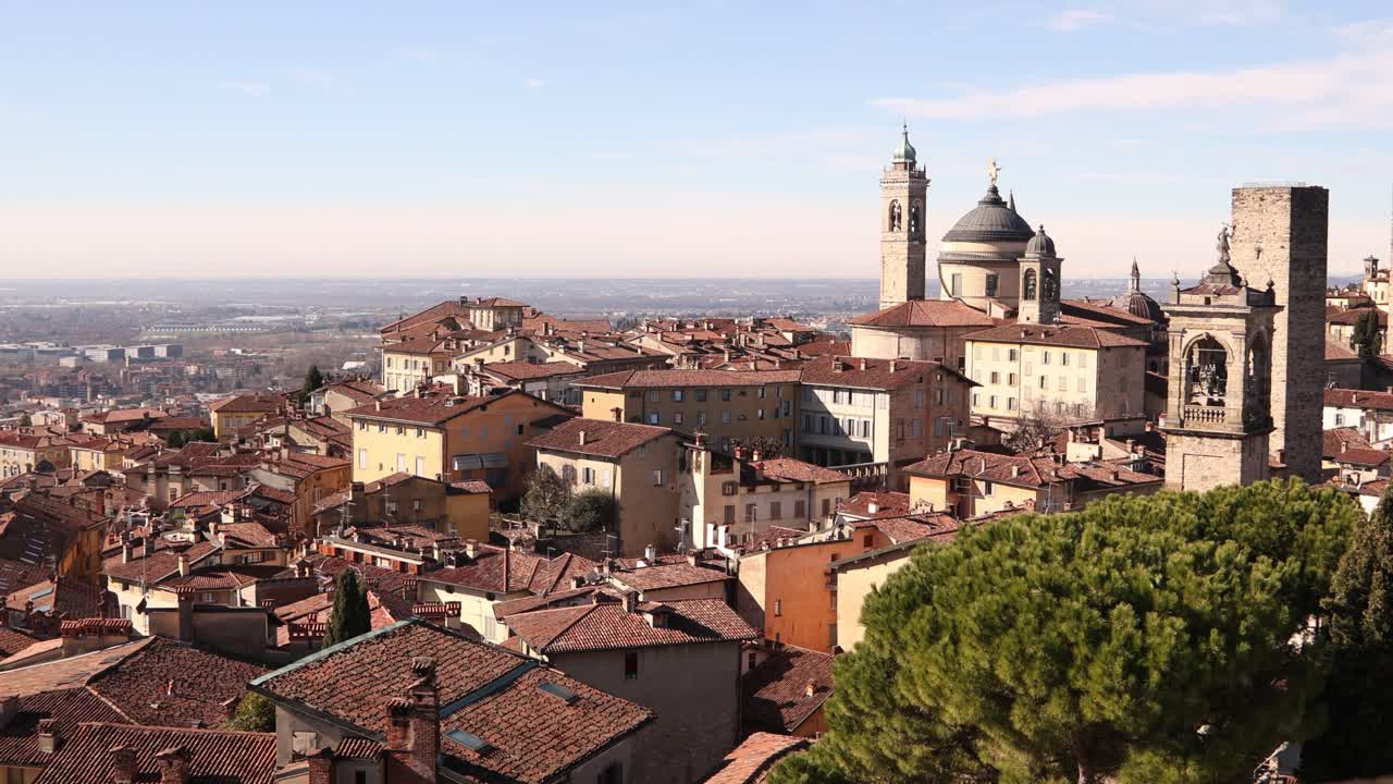 Ampia ripresa panoramica della storica Città Alta a Bergamo, con antichi tetti in terracotta e una vista estesa sulla circostante regione Lombardia.
