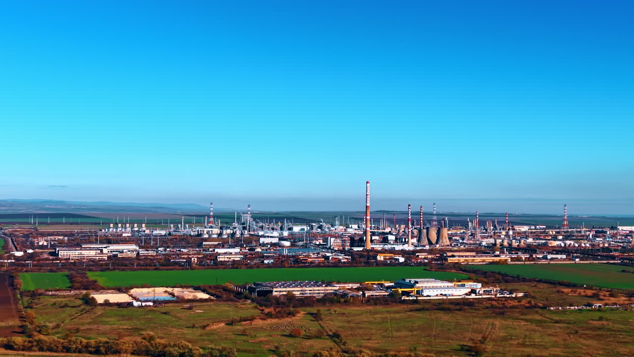Industrianlegg for råoljeforedling på landsbygda. Grønne jorder omgir raffineriets område. Luftfoto