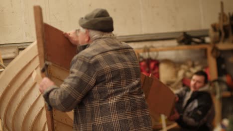 nailing a template onto a wooden frame as part of traditional boat construction process.