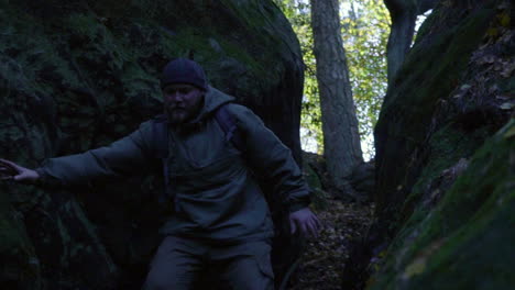 man hiking downhill between giant rocks during adventure trip