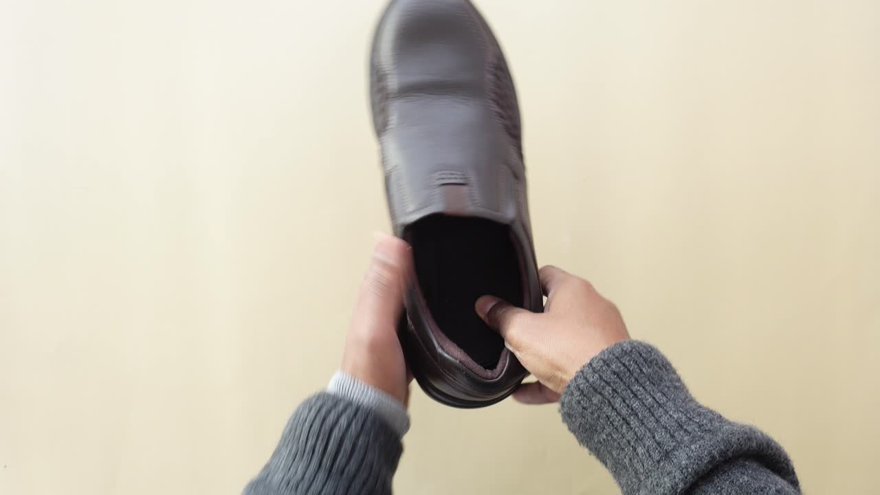 갈색 가죽 신발 한 을 들고 있는 남자