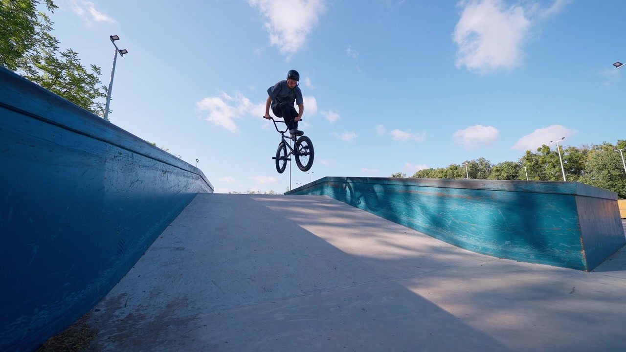 Młody mężczyzna wykonujący skok na rowerze BMX w skateparku