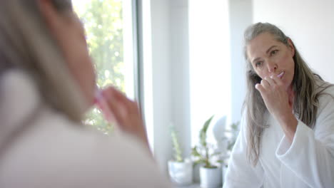 Mature-Caucasian-woman-applying-makeup-in-front-of-mirror