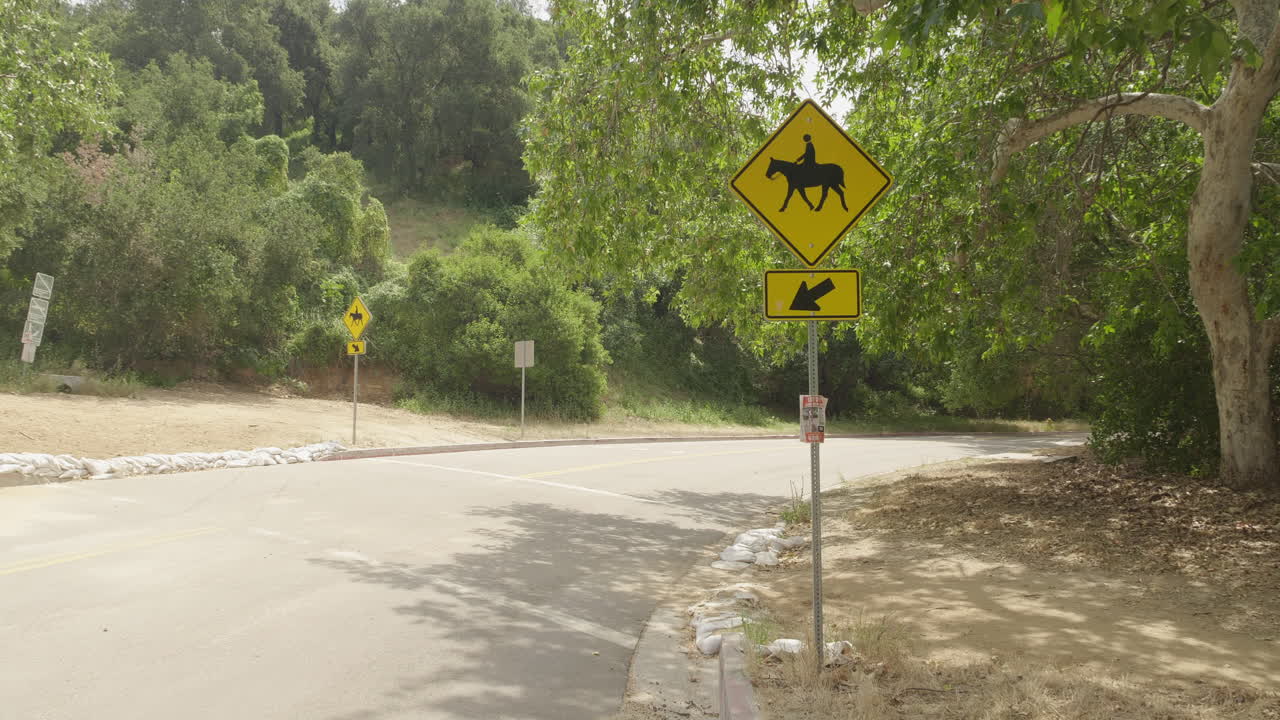 Dettagliato filmato diurno 4K 10-bit DSLR a campo medio di un segnale di attraversamento cavalli lungo Griffith Park Drive a Los Angeles.