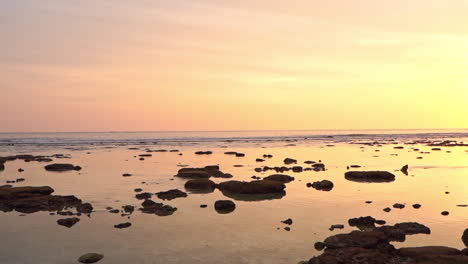puesta de sol idílica sobre mar tranquilo y playa tropical escondida con siluetas de rocas