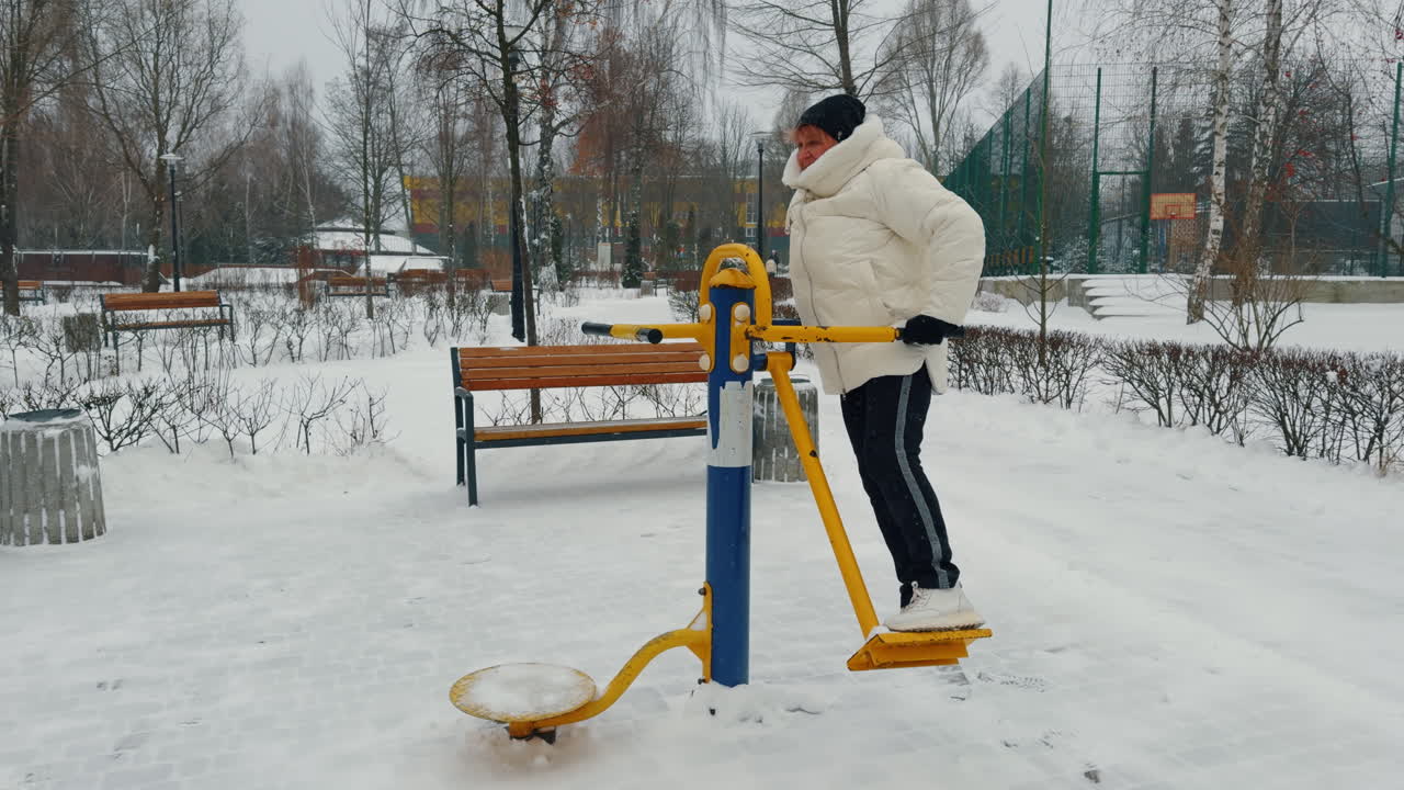 Woman practicing on the simulator on the sports ground. Senior woman doing sport in winter.