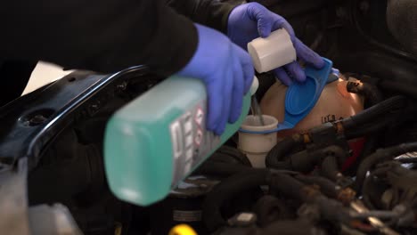 a technician fills a vehicle washer bottle (no logos only coshh symbols)