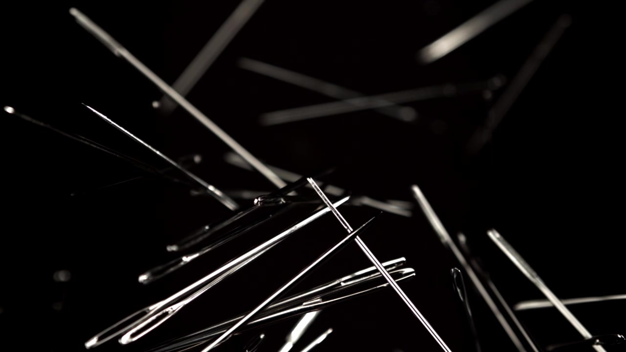 Metallic Sewing Needles Focusing Against a Black Background
