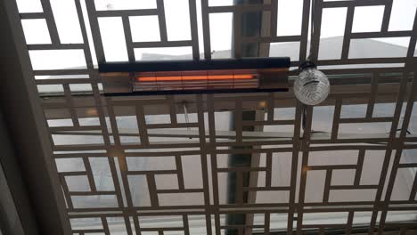 close-up of a heater and light fixture on a ceiling with a metal grid design