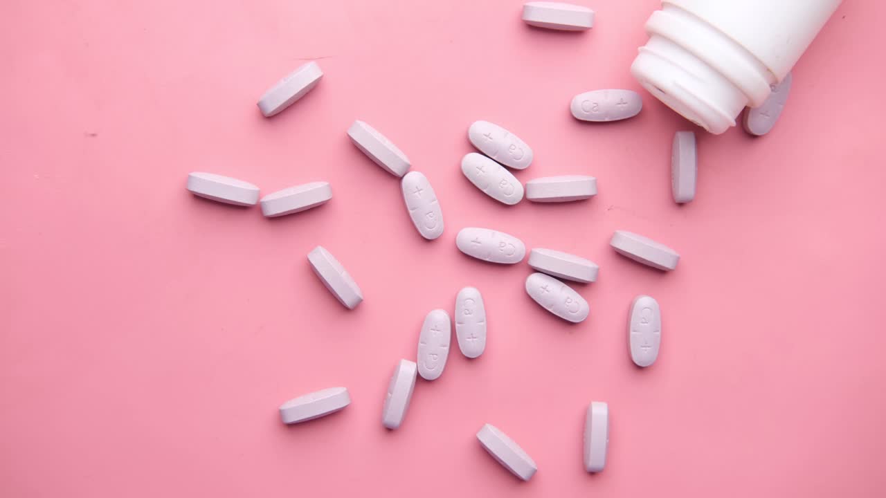 fondo rosa con pastillas y botella de color púrpura claro