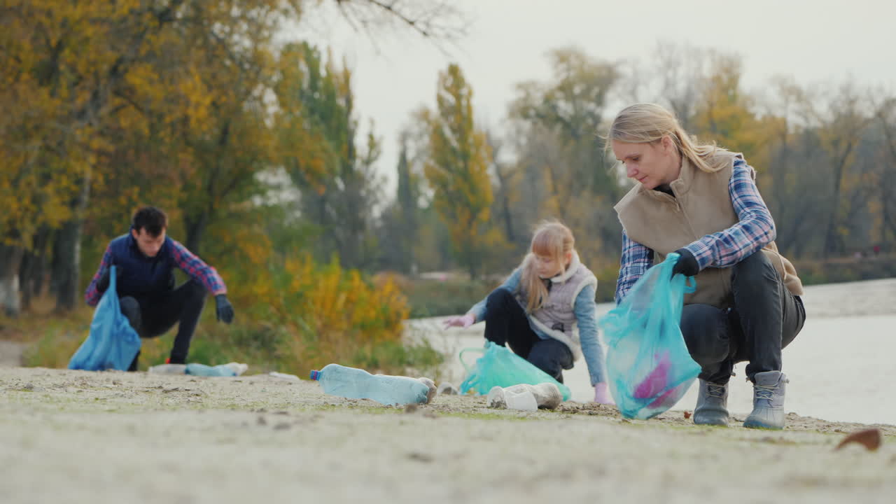 La famiglia raccoglie rifiuti di plastica sul lago: un concetto per un ambiente pulito