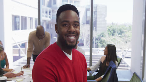 Portrait-of-happy-african-american-businessman-over-diverse-business-colleagues-discussing