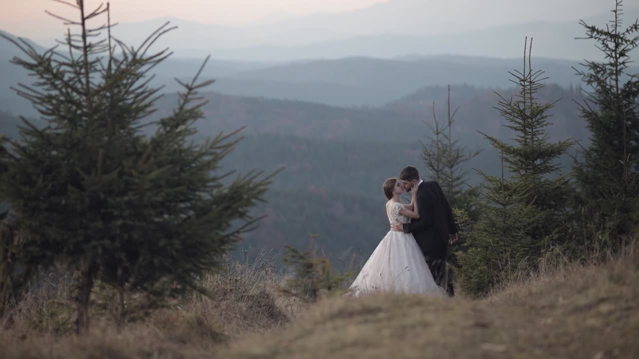 recién casados. novio caucásico con la novia en la ladera de la montaña. pareja de bodas. felices