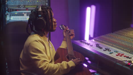 african american man playing guitar and singing in recording studio