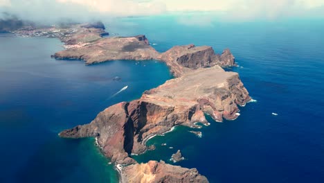 Vista-De-Pájaro-De-Una-Isla-Con-Océano-Azul-Y-Un-Barco-En-La-Distancia