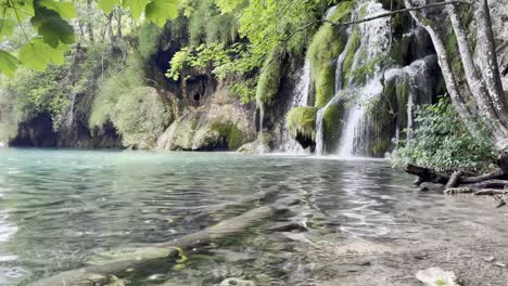 panorámica desde el hermoso agua clara hacia la cascada en la barrera de tufa en el parque nacional de los lagos de plitvice, croacia