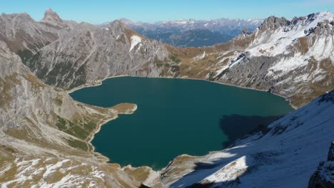 una toma de drone del lago heart love en suiza, moviéndose hacia atrás y revela a un joven, de pie fuerte y orgulloso en la cima de un acantilado y mira hacia el paisaje impresionante delante de él