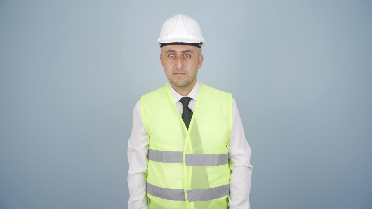 el ingeniero mira a la cámara y hace una señal de alto.