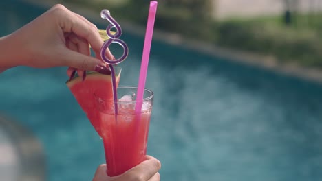 girl holds juicy watermelon cocktail with colorful straws