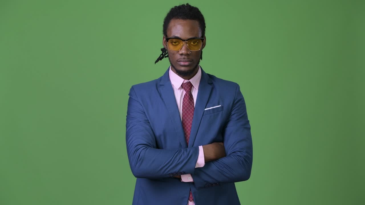 joven empresario africano guapo con dreadlocks contra un fondo verde