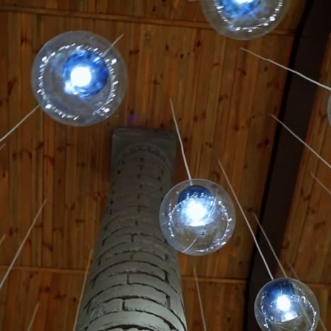 modern ceiling with light lamp balls. many round light balls hanging around brick column in the hall. beautiful glass bulbs on brown background.