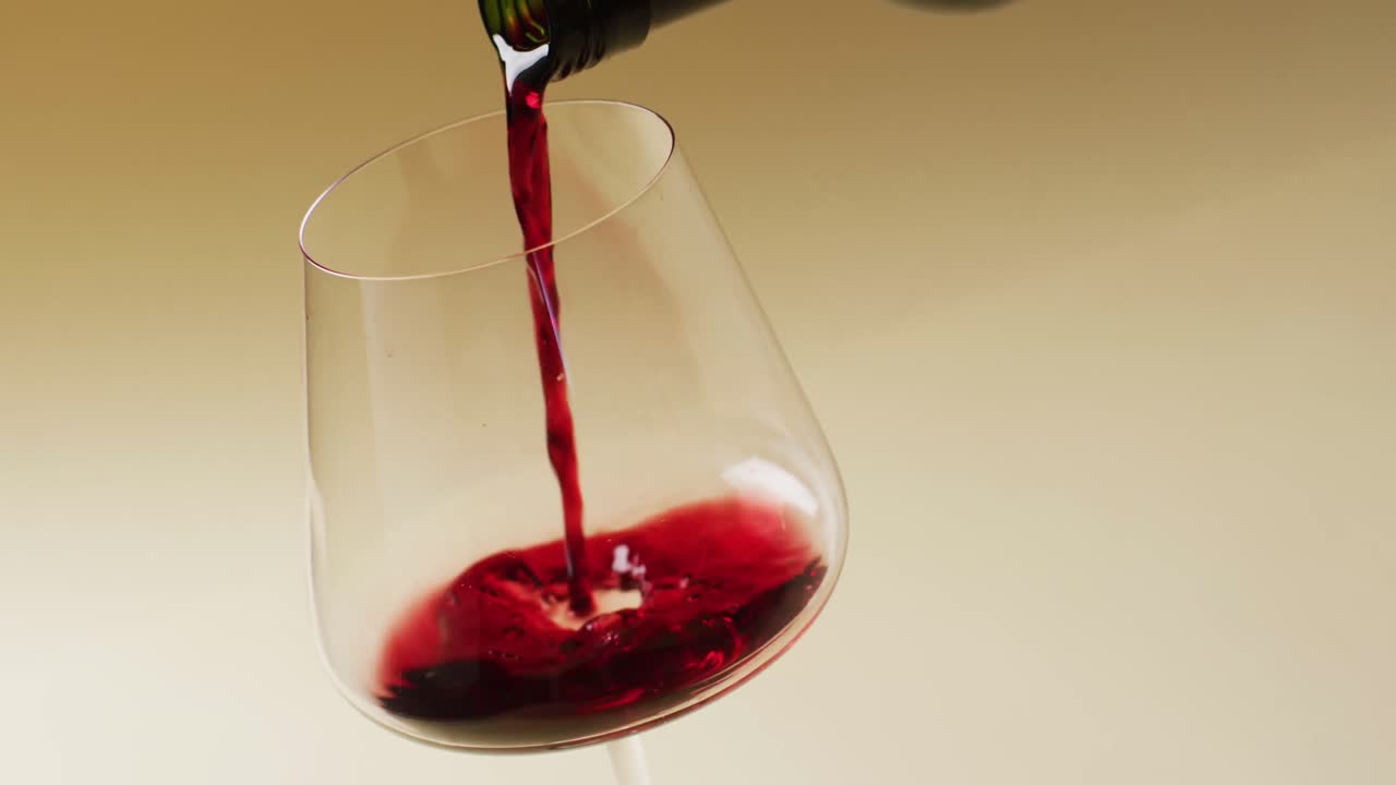 Vino rosso che si versa nel bicchiere su sfondo giallo con spazio per il testo
