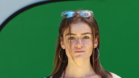 joven guapa morena con gafas de sol posando frente a una pantalla verde, foto de retrato