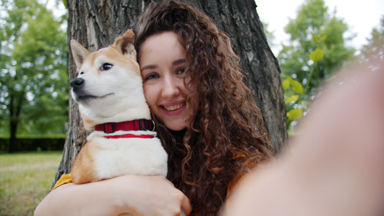 Woman taking a selfie with her Shiba Inu dog in a park