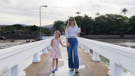 mother and daughter walking on a pier