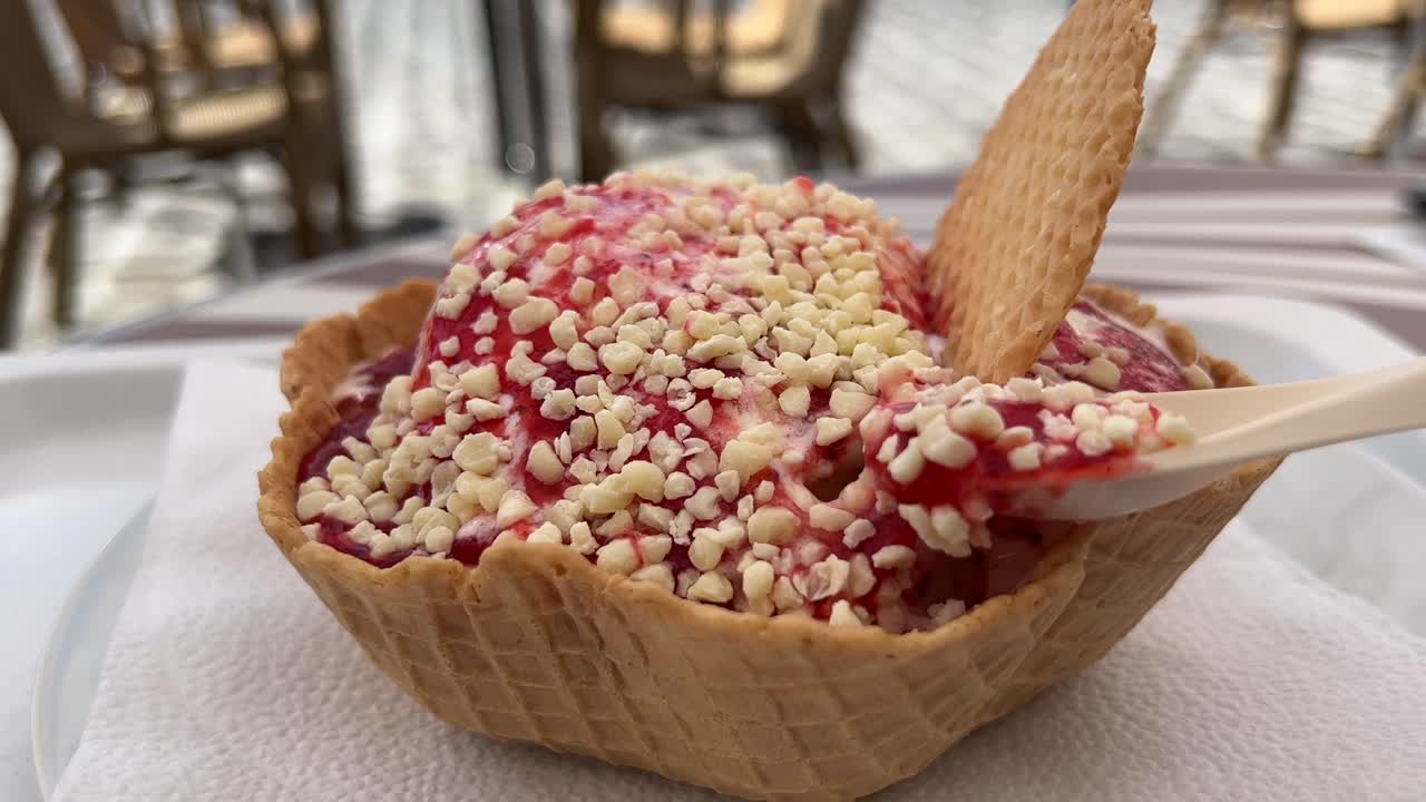 Eating spaghetti ice cream with strawberry sauce and white chocolate close up