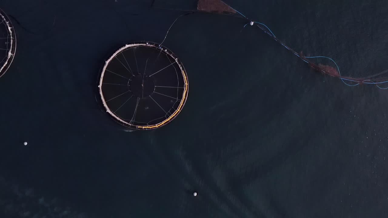 Bird's eye view drone shot of a fish farm, a fishing boat and a well-boat