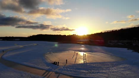 aerial view of people playing outdoor hockey on a frozen lake in the winter during sunset