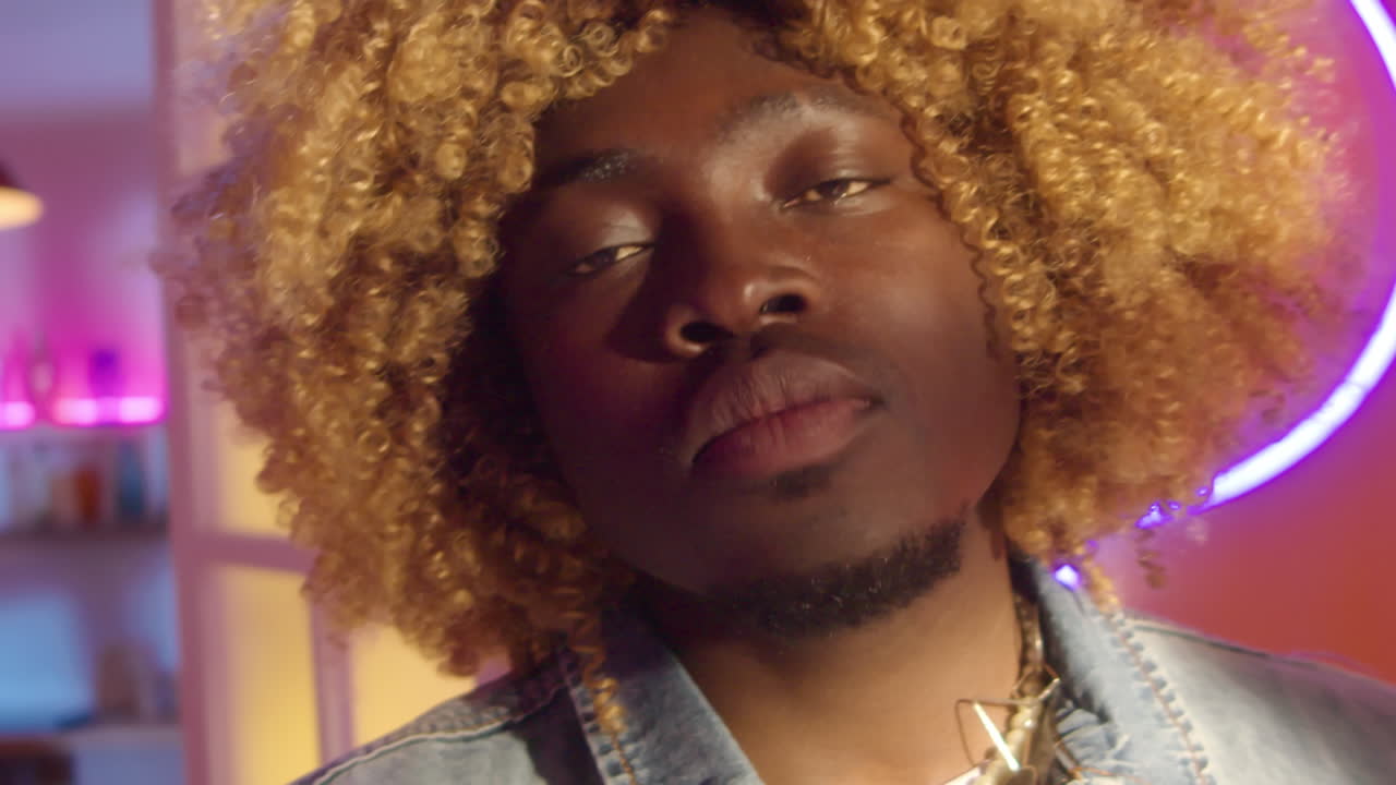 Man with Curly Blonde Wig in a Colorful Studio Setting