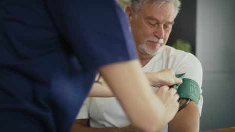 Caucasian-female-doctor-measuring-pressure-of-senior-man-at-home-visit.