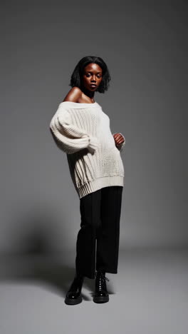 stylish fashion model in off-shoulder knitted sweater and black pants