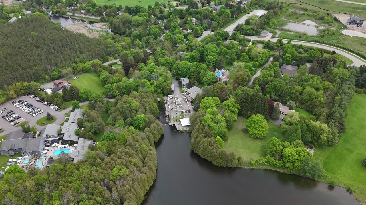 Reveal drone shot of Millcroft Inn and Spa with a lake during the day in Alton, Caledon, Ontario, Canada