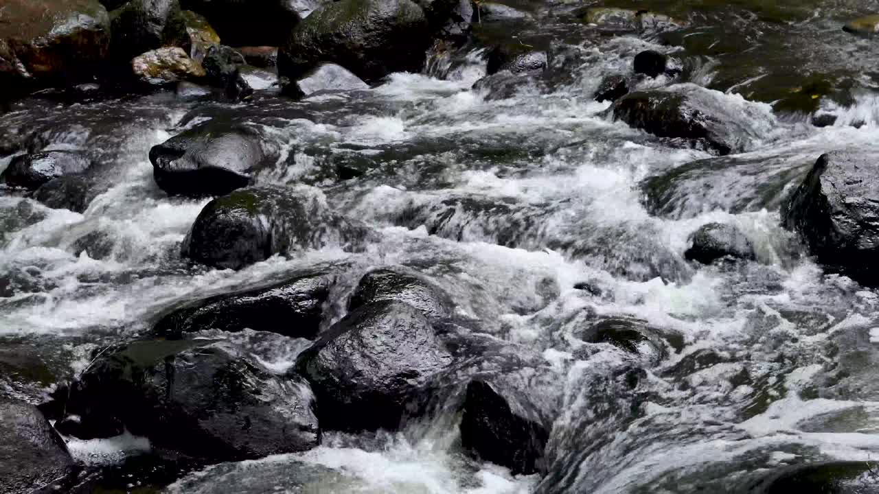 Elv med sterk strøm over svarte steiner