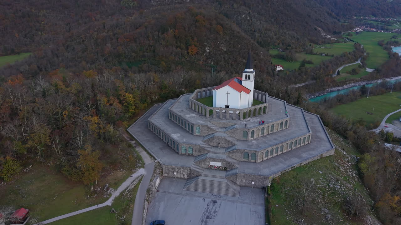 Aerial circling shot of the First World War memorial with St Anton Church and the Soca river