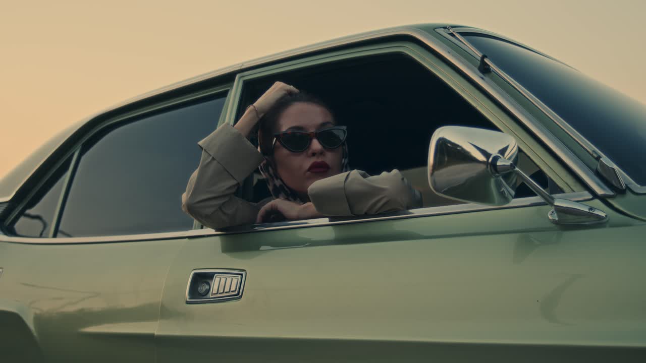 Mujer conduciendo un coche clásico al atardecer