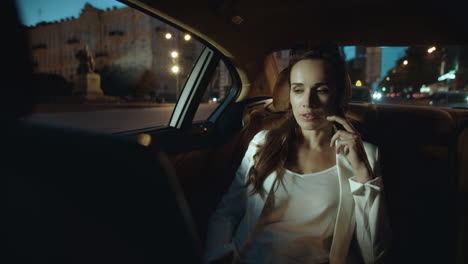 Calm-business-woman-talking-on-smartphone-in-dark-salon-of-business-car.