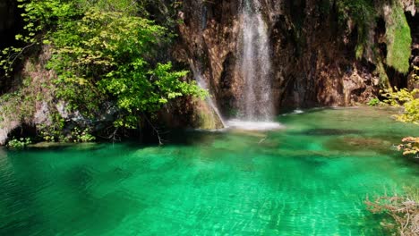 Waterfall-Flowing-Over-Rocks-Into-A-River-With-Turquoise-Water---aerial