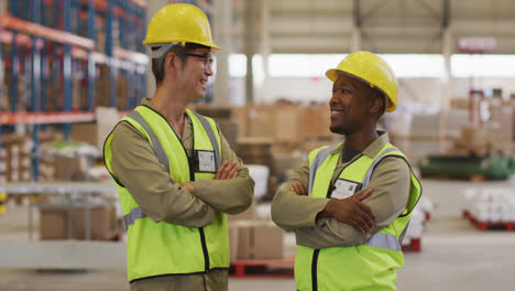 portrait of diverse male workers wearing safety suits and smiling in warehouse