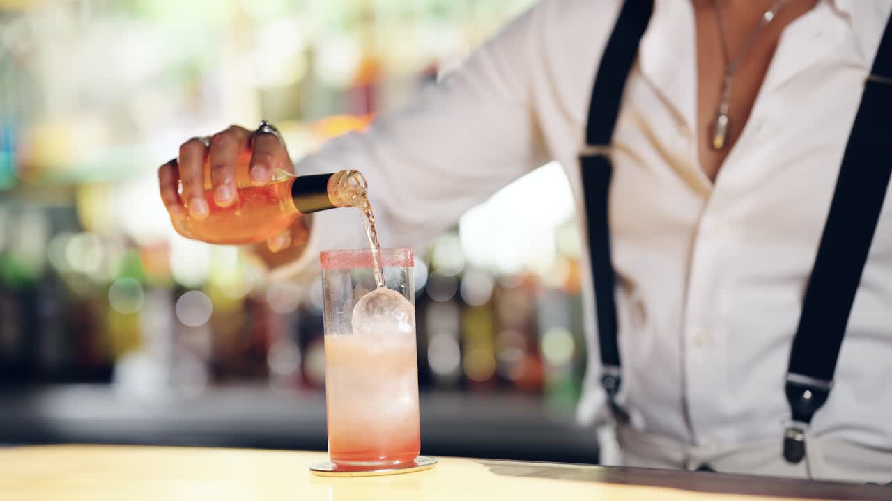 Bartender hælder en forfriskende cocktail i et glas med is