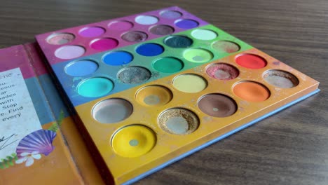 colorful makeup palette with various shades on a wooden table, close-up shot