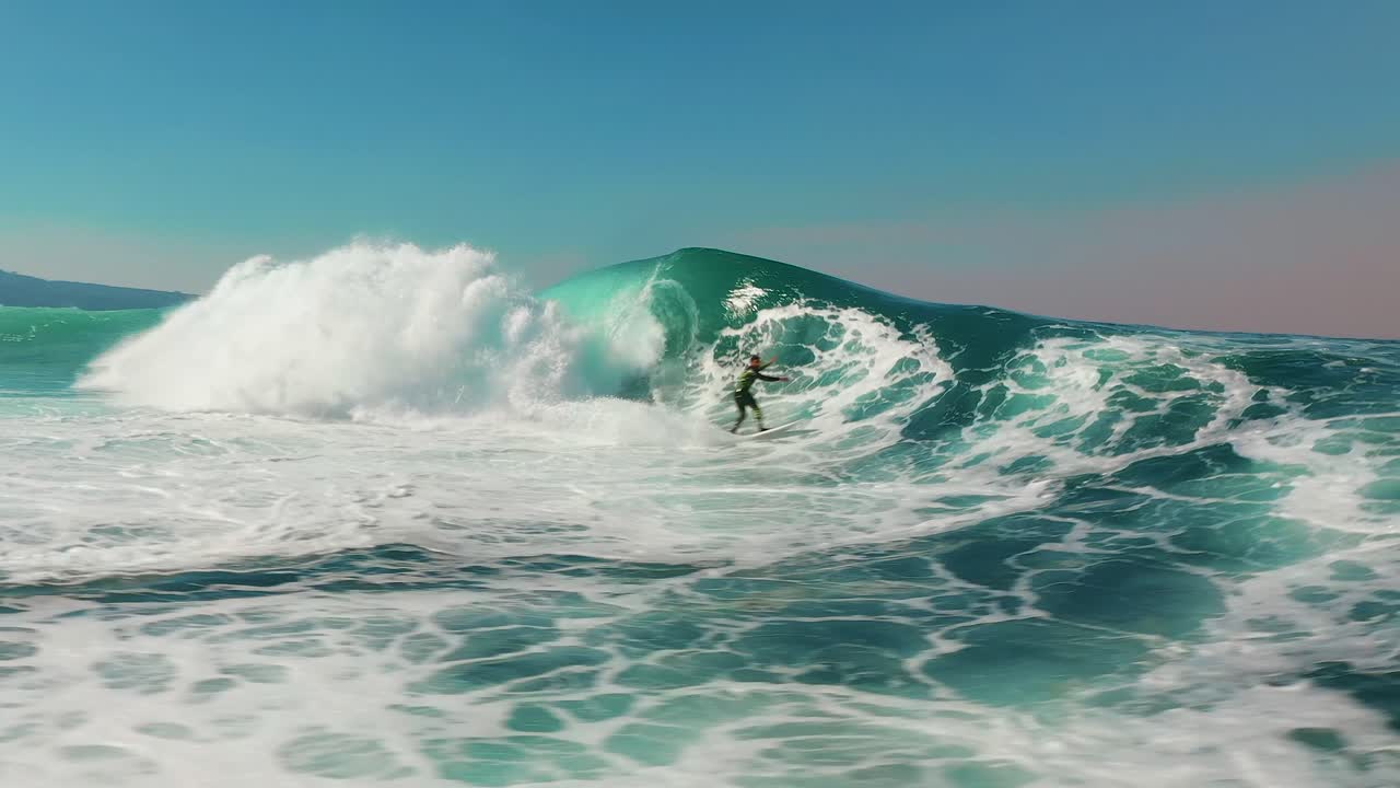 Surfer catches big ocean wave in slowmo. Aerial view of surfing on Australian coast