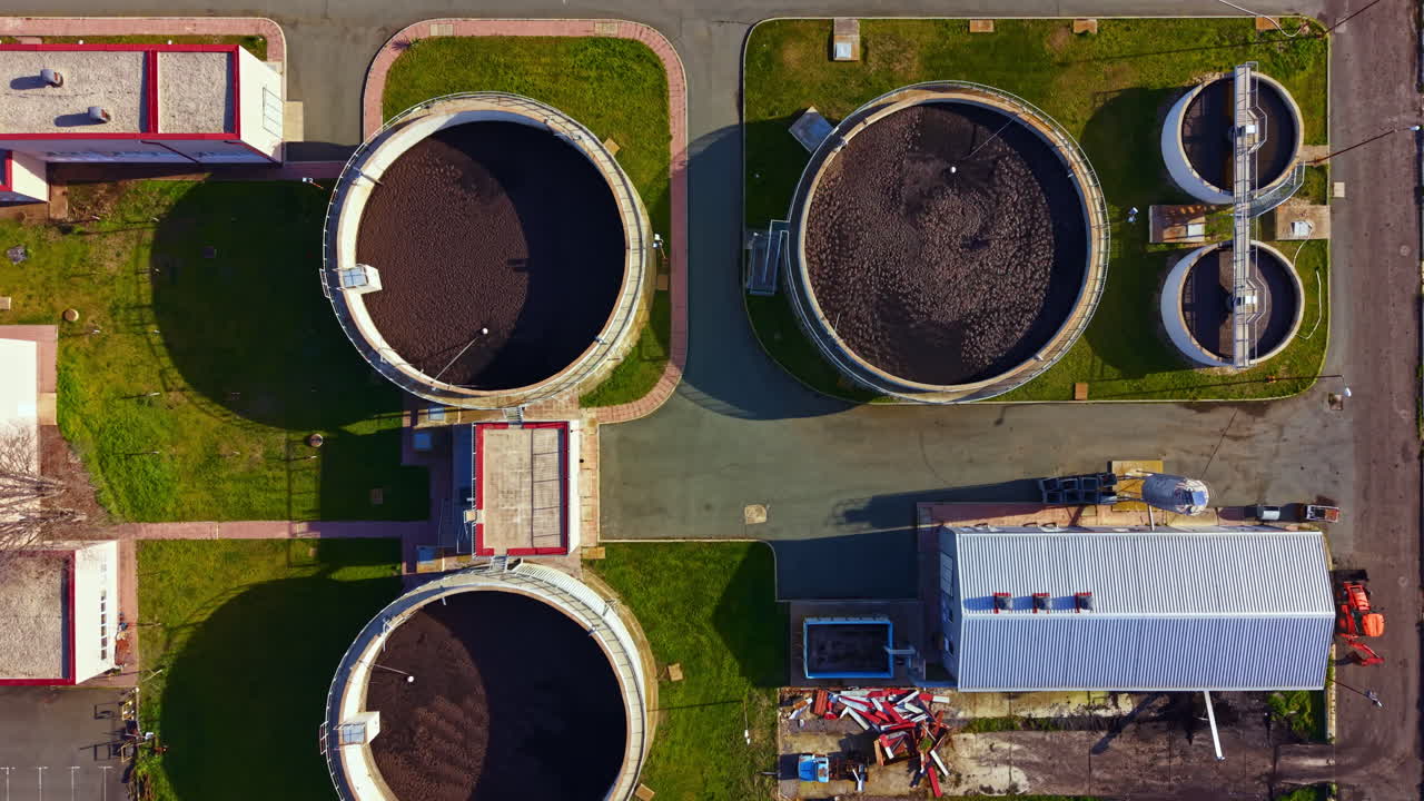 Workers gather at a wastewater treatment facility for maintenance and inspection of tanks during daytime operations in a rural area