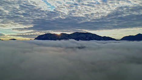 The-rising-sun-just-shines-over-the-mountain-peaks,-which-are-shrouded-in-clouds