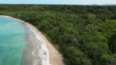 Flight-over-a-paradisiacal-beach-with-turquoise-water-bordered-by-a-jungle